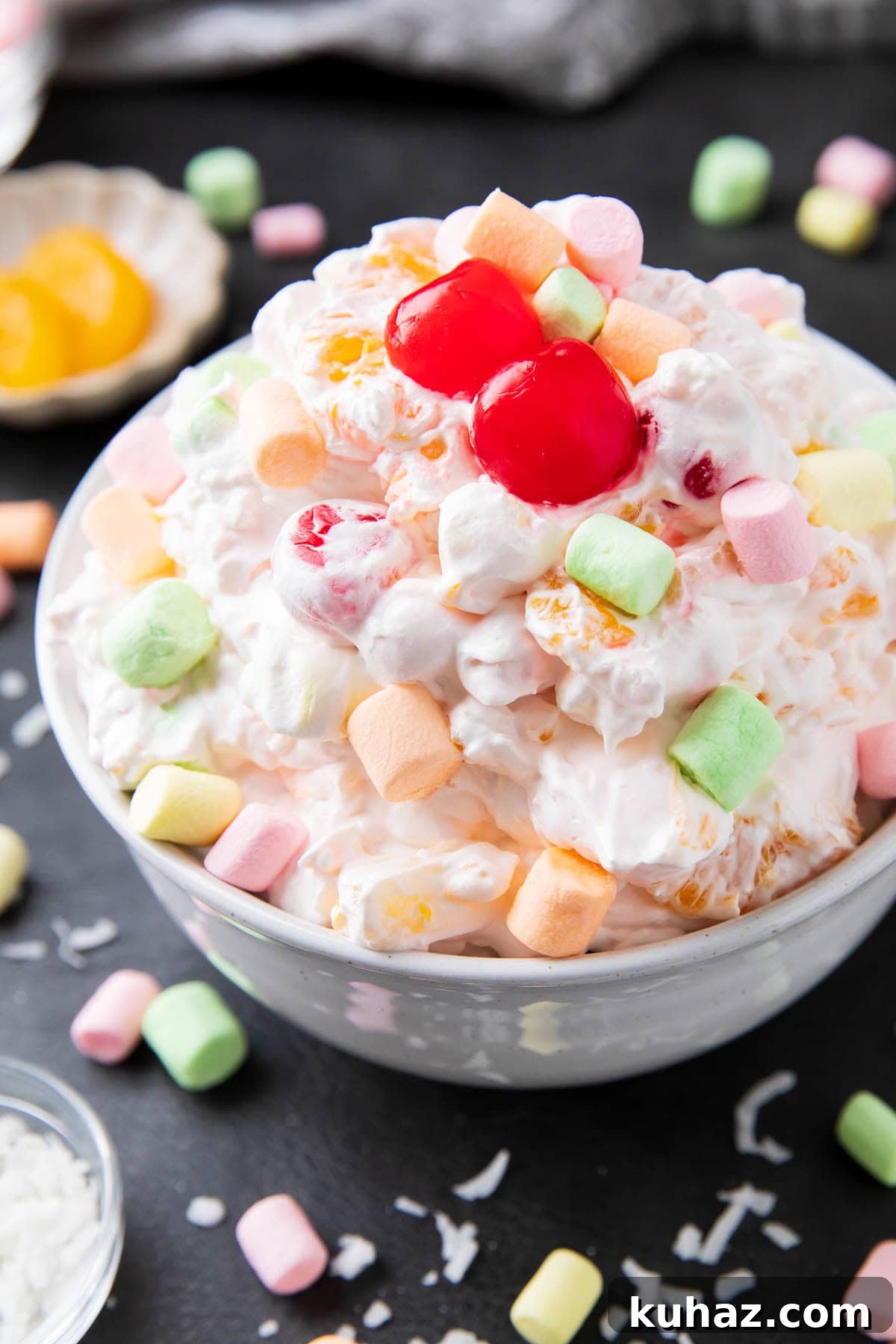 Ambrosia salad is creamy and covered in Cool Whip with marshmallows and fruit cocktail ingredients in a bowl.