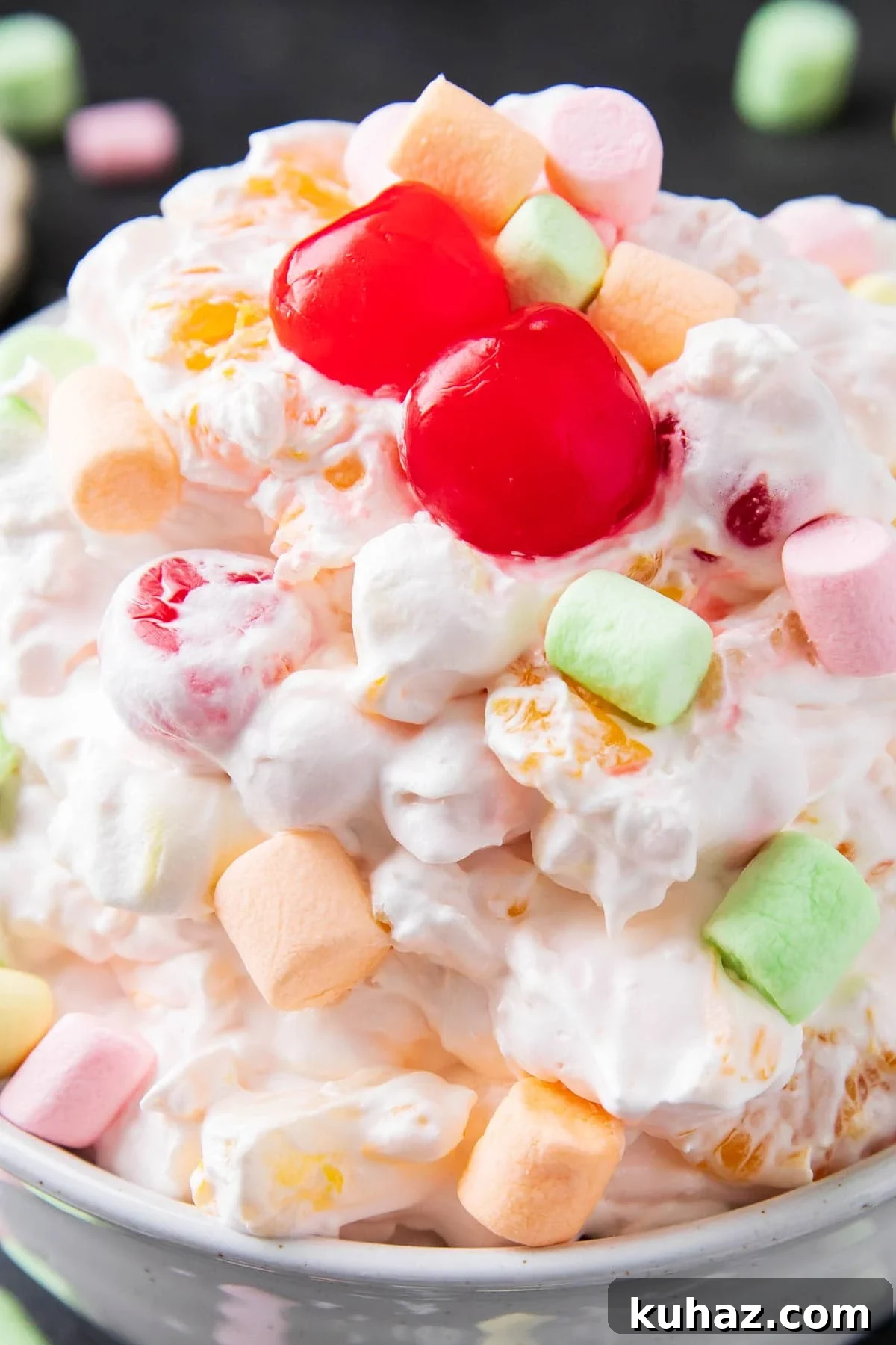 Close up of Ambrosia fruit salad to show sweet fruit salad dessert-like texture with sweet coconut, marshmallows, mandarin oranges, cherries, and pineapple.