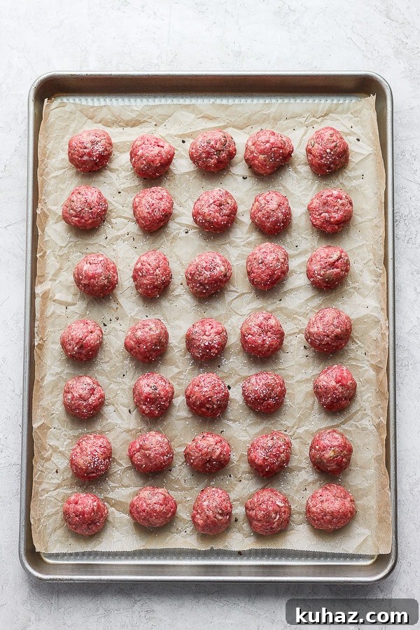 Raw Meatballs on Baking Sheet Meatballs on a parchment-lined baking pan before cooking.