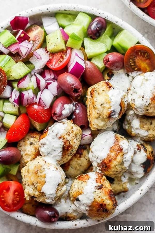 Juicy Oven Baked Meatballs Recipe 4 A bowl of greek chicken meatballs with tzatziki sauce and a greek cucumber salad.