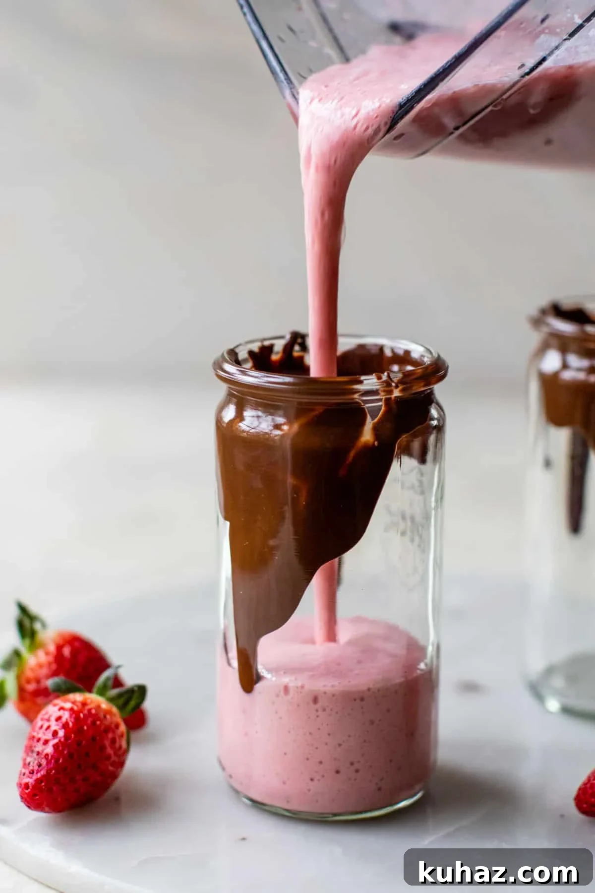 Creamy Chocolate Covered Strawberry Smoothie Recipe 3 someone pouring a pink smoothie from a blender into a glass