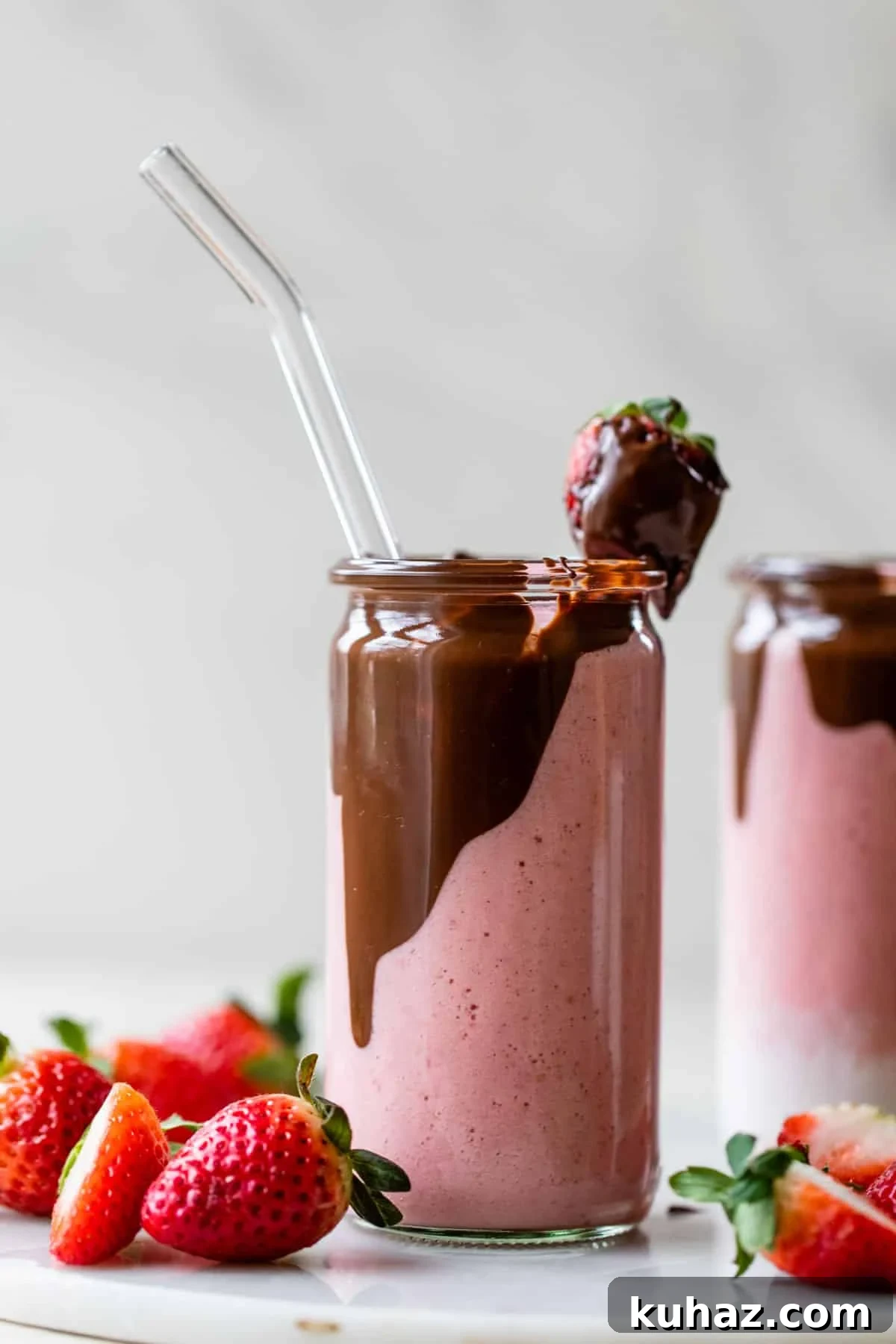 Creamy Chocolate Covered Strawberry Smoothie Recipe 5 glass filled with a pink-colored smoothie with chocolate on the inside and a chocolate covered strawberry on top