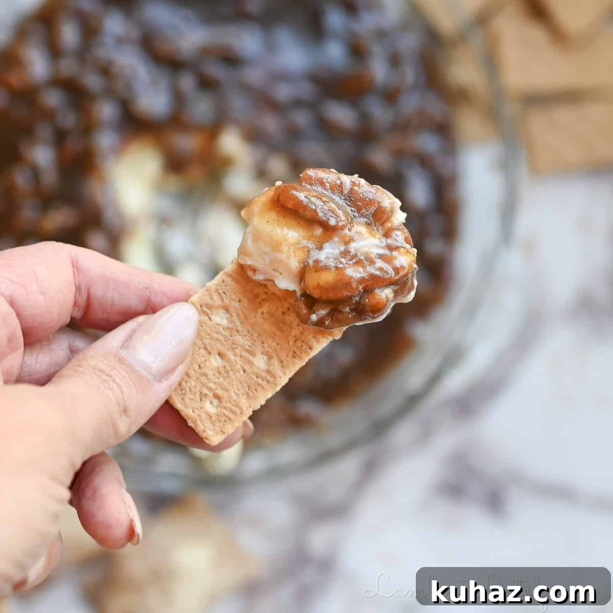 No Bake Pecan Pie Dip with Cream Cheese 2 holding pecan pie dip, featuring creamy base and gooey pecan pie layer, on a graham cracker.