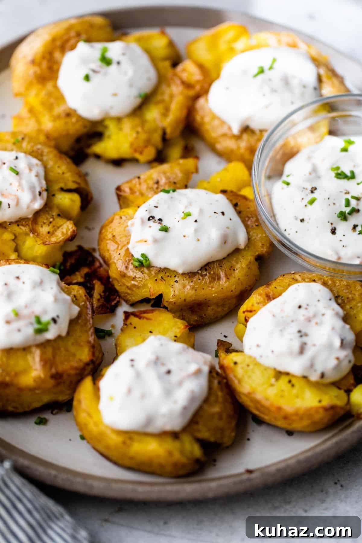 Crispy Smashed Potatoes with Sour Cream Recipe 6 overview of crispy smashed potatoes on a plate with dollops of garlic cheddar sour cream on top