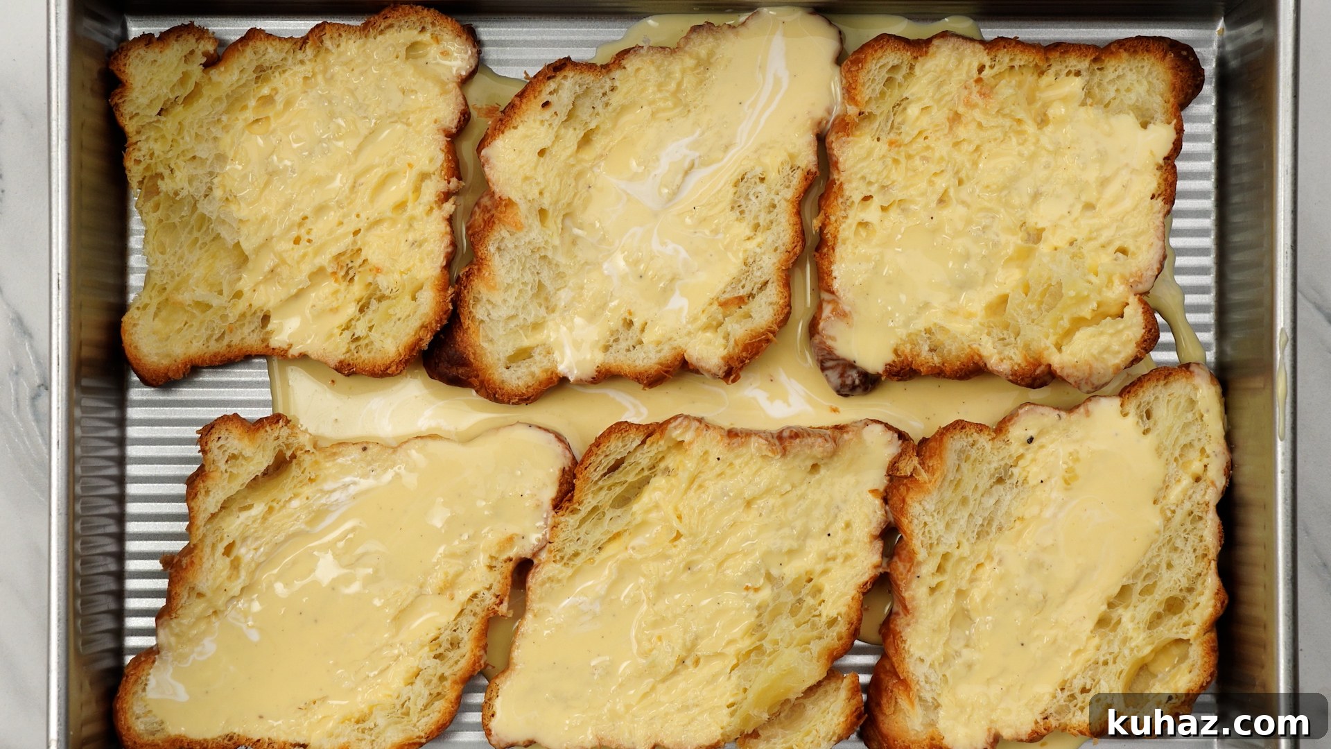 Make-Ahead Ham and Cheese Croissant Breakfast Casserole 7 Egg-milk mix poured over halved croissants.