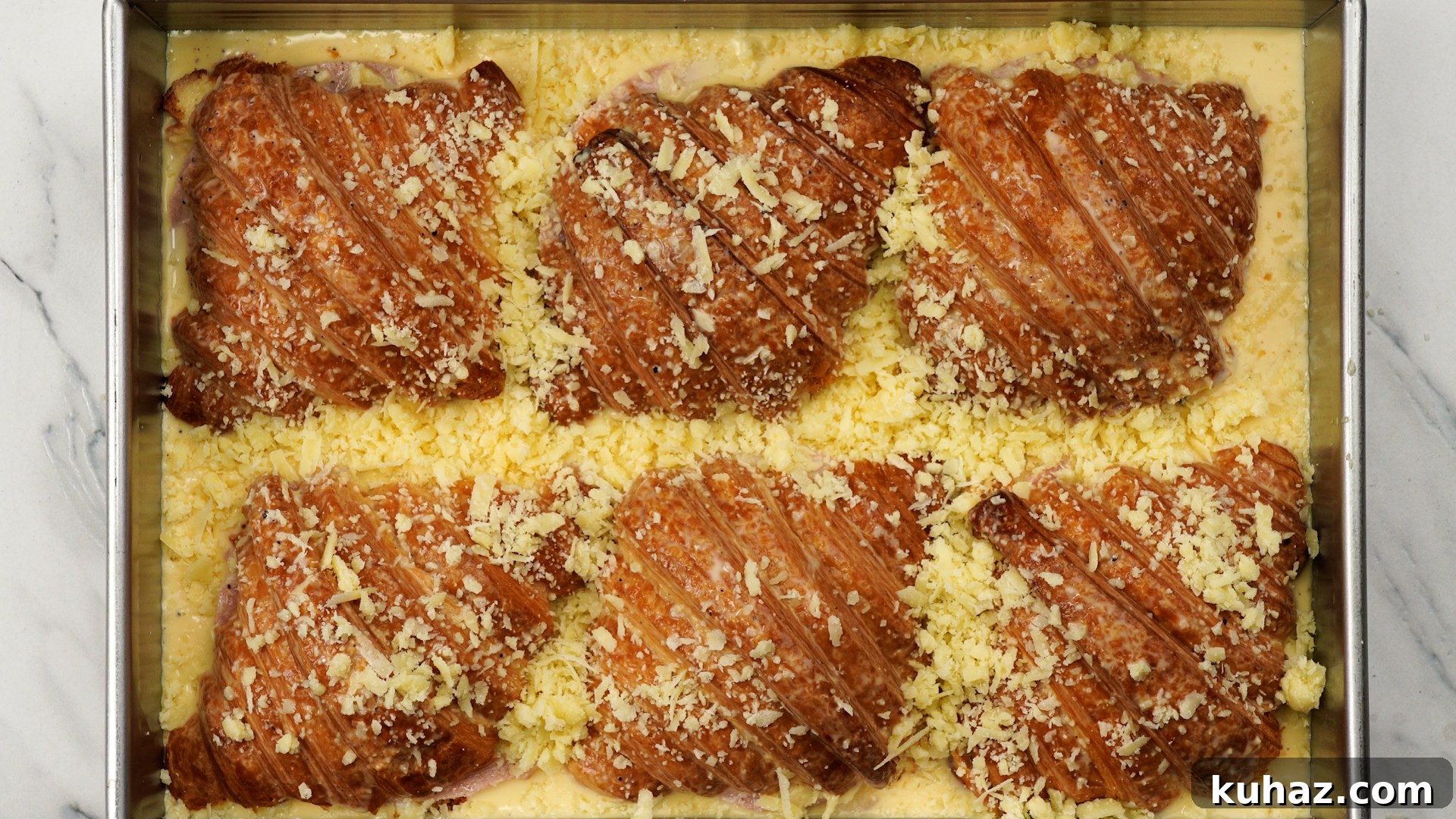 Make-Ahead Ham and Cheese Croissant Breakfast Casserole 9 Egg-milk mixture poured over ham and cheese croissants and cheese sprinkled on top.