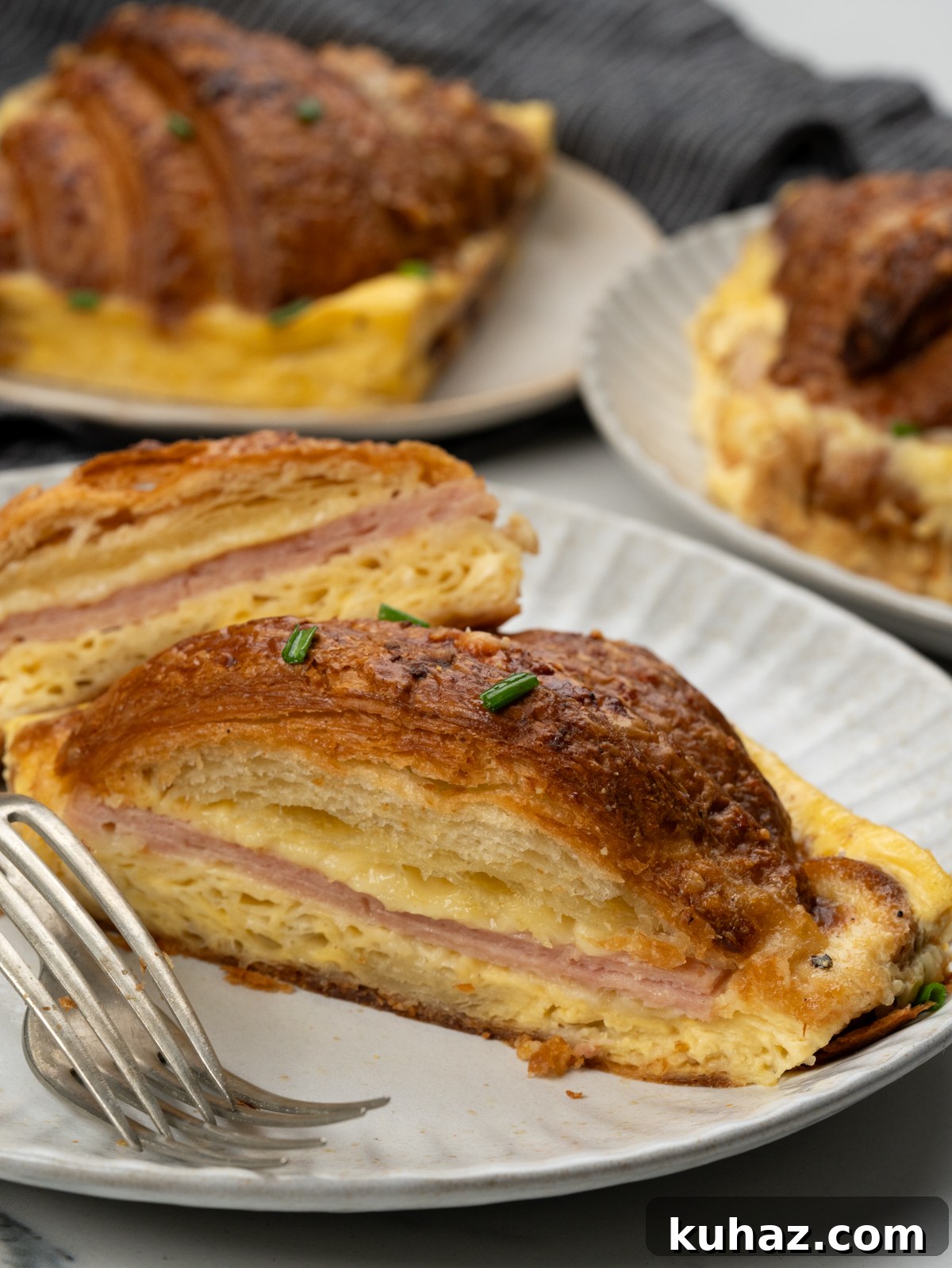 Make-Ahead Ham and Cheese Croissant Breakfast Casserole 10 A large chunk of breakfast croissant casserole showing layers of ham and cheese in between.