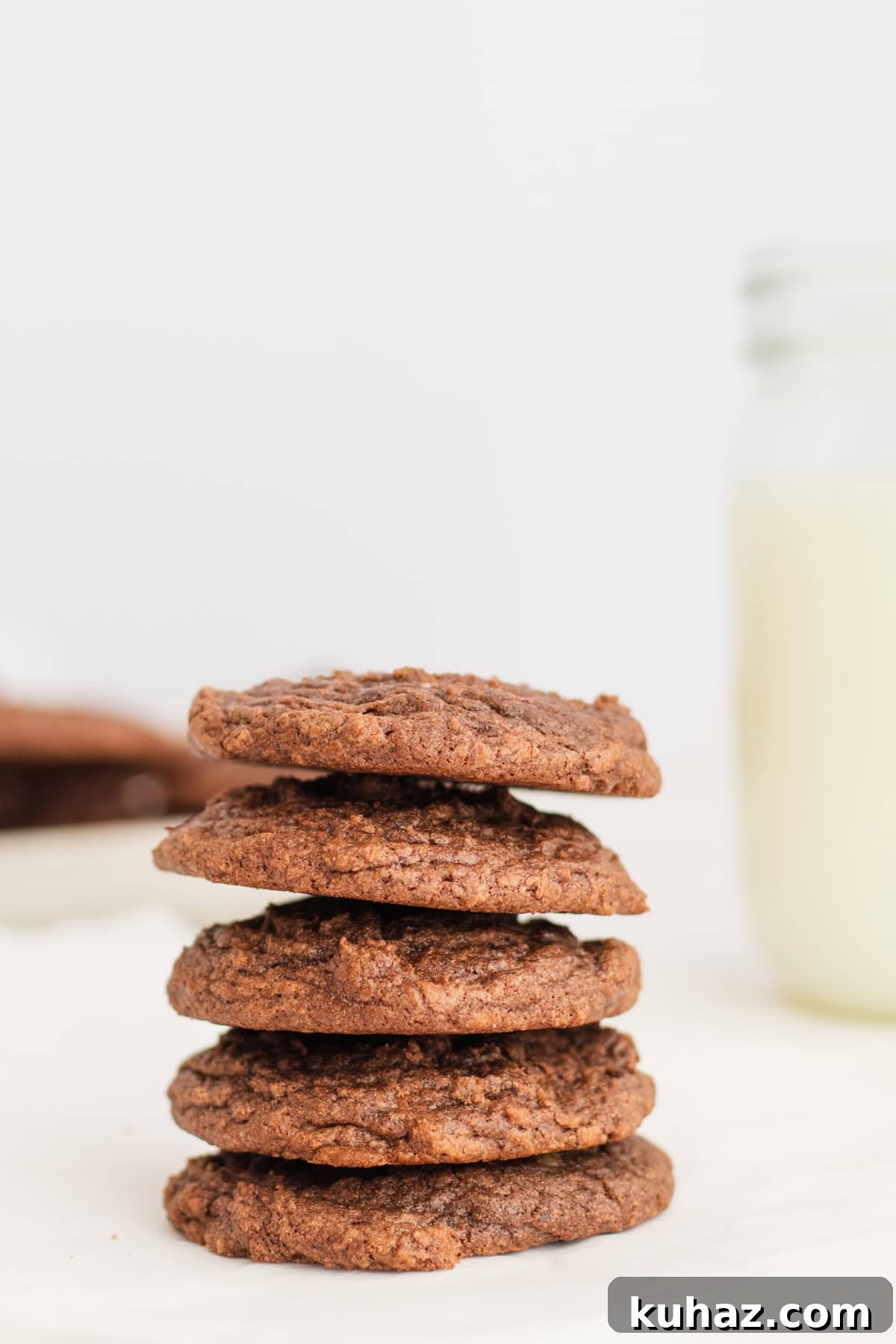 Chewy 4-Ingredient Brownie Mix Cookies 2 brownie mix cookies stacked 5 high with a glass of milk in background.