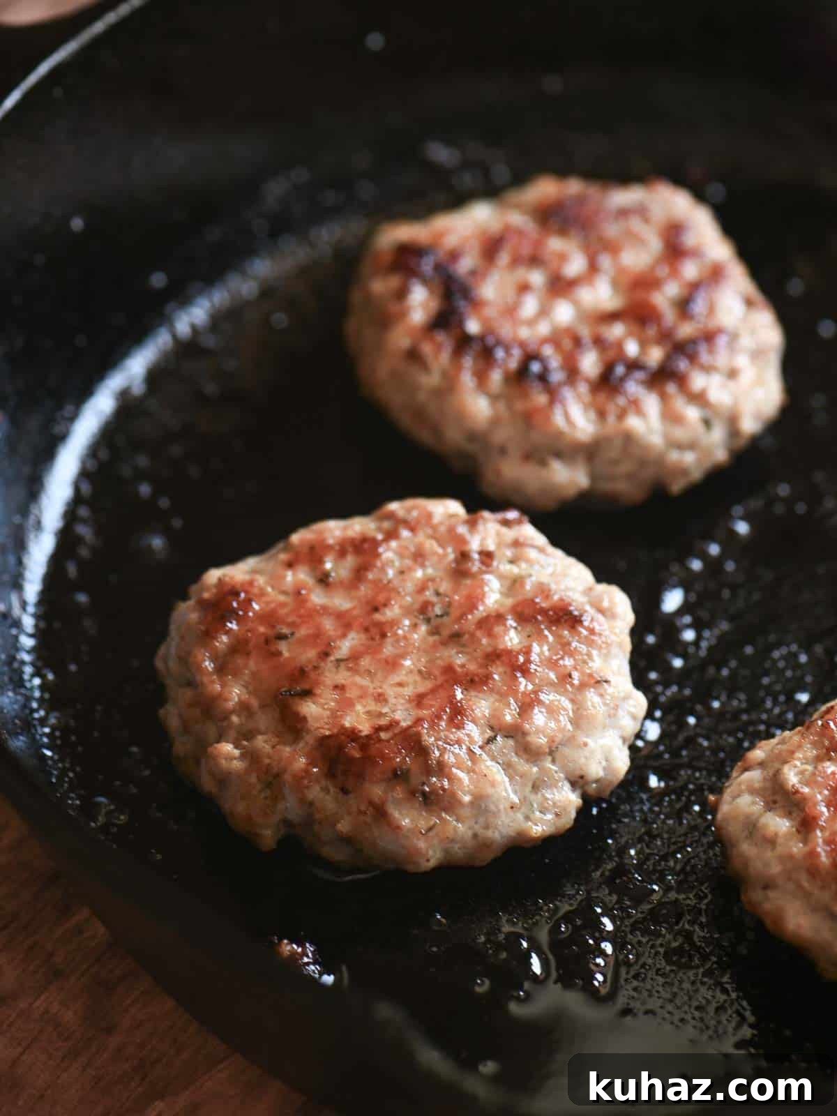 Homemade Maple Sage Breakfast Sausage Patties Recipe 3 Breakfast sausage patties in a cast iron skillet.