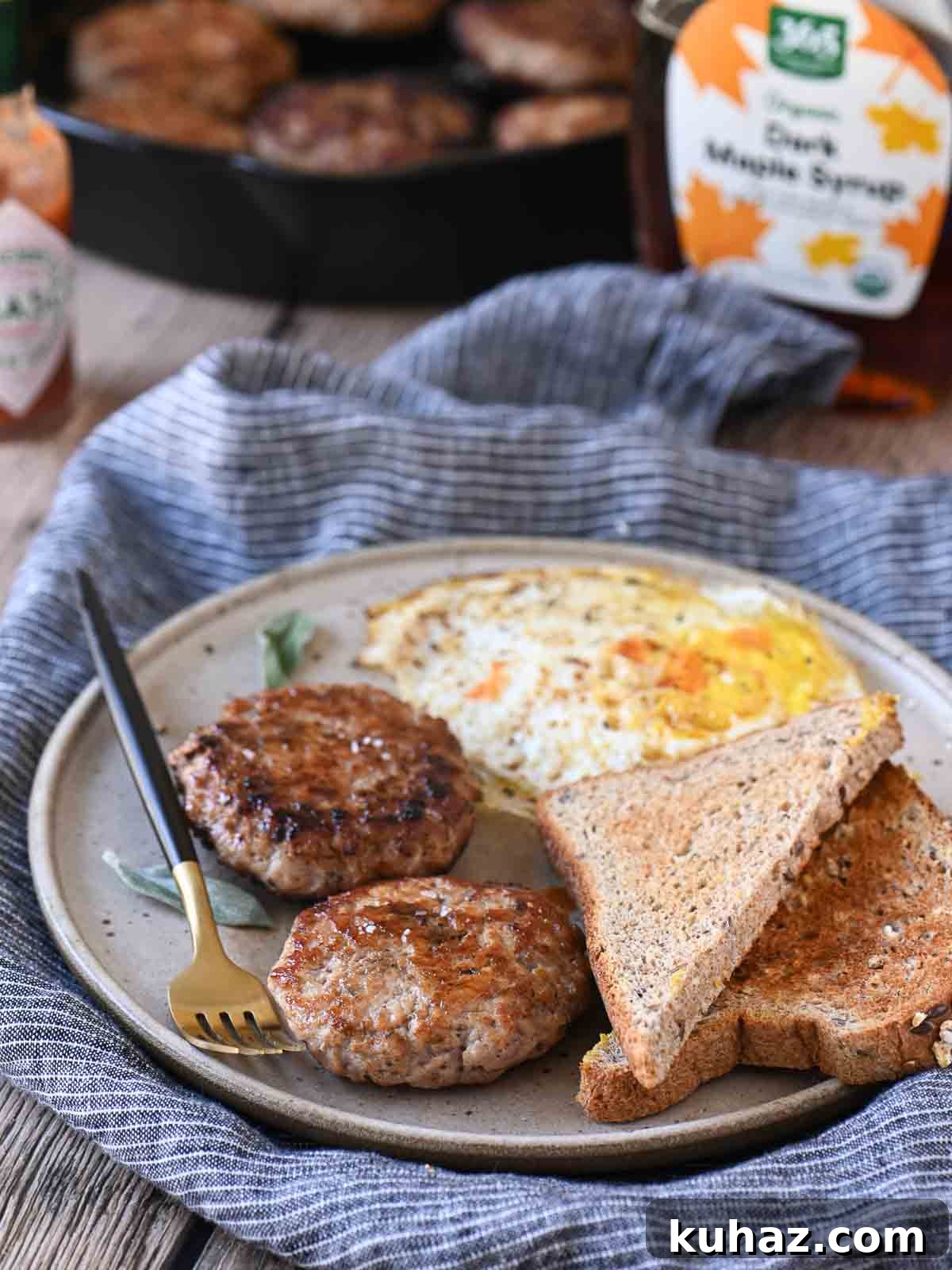 Homemade Maple Sage Breakfast Sausage Patties Recipe 5 Angled view of sausage patties, eggs, and toast on a beige plate with a fork to the left.