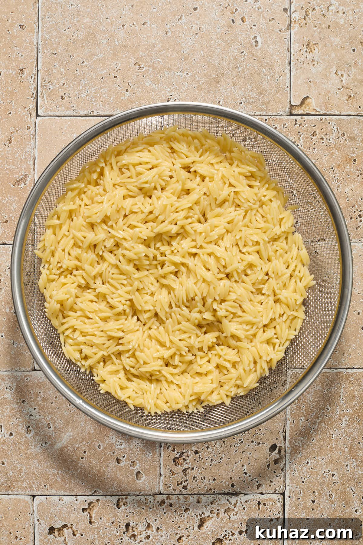Cooked orzo in a mesh strainer.
