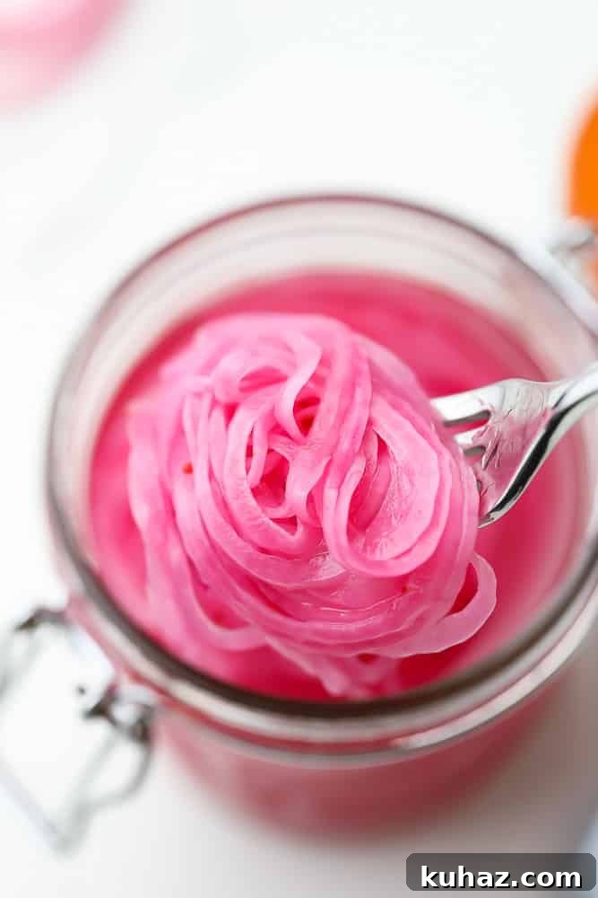 Pickled Red Onions Recipe for Tacos, Salads and Sandwiches 2 close up of a fork taking a scoop of pickled red onions out of a mason jar