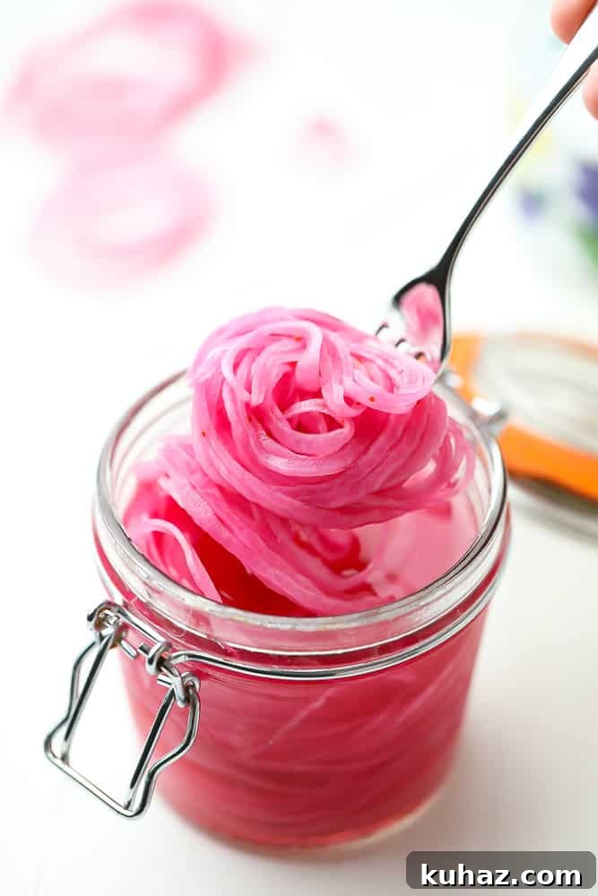 Pickled Red Onions Recipe for Tacos, Salads and Sandwiches 3 scooping pickled red onions out of a jar with a fork