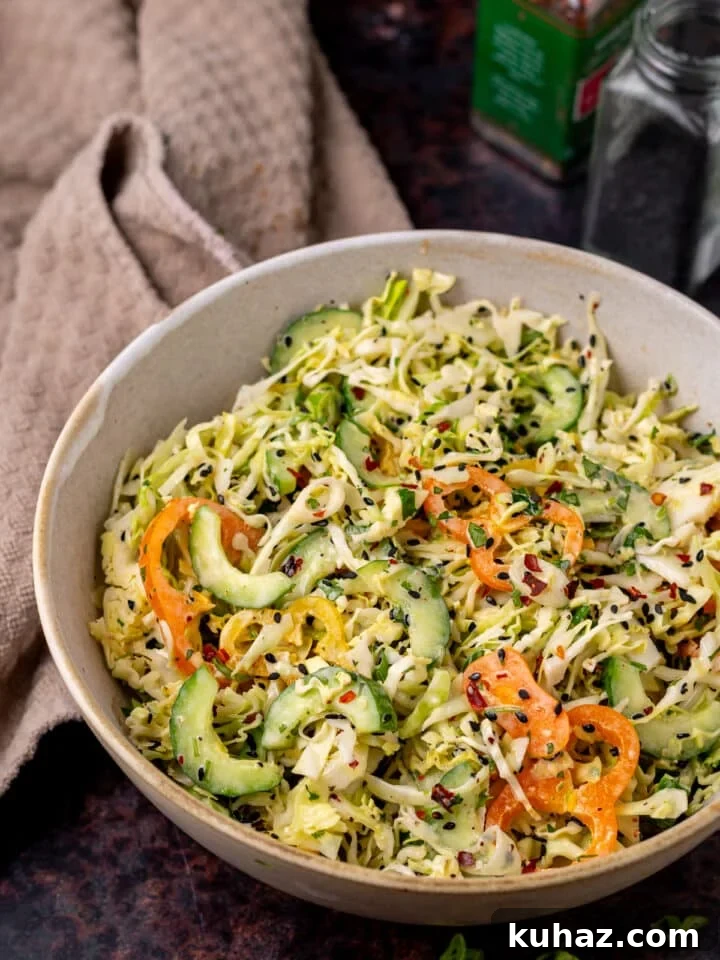Large bowl with thinly sliced cucumber, peppers, cabbage, sesame seeds and creamy sweet chili dressing