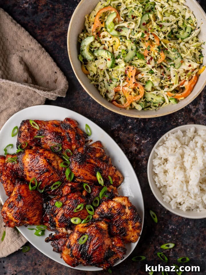 white platter of miso chicken thighs, large bowl of Asian cucumber slaw, small bowl of rice