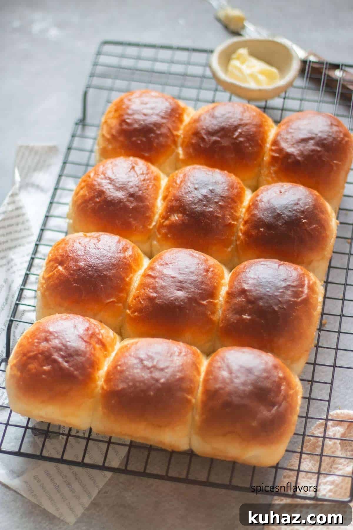 Fluffy Homemade Bread Machine Dinner Rolls Recipe 10 baked dinner rolls placed on a wire rack with butter bowl and knife on the side