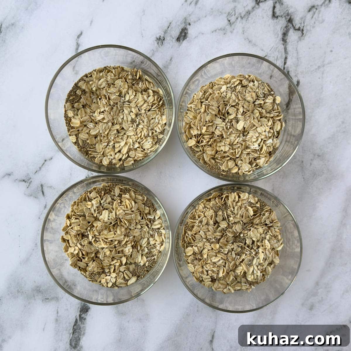 High-Protein Overnight Oats with Chia Seeds Recipe 4 Four glass bowls with dry rolled oats and chia seeds ready for milk and vanilla.
