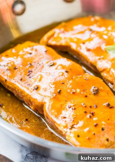 Two glazed salmon fillets in a pan.