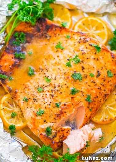Oven-baked salmon fillet seasoned with spices, garnished with parsley and lemon slices.