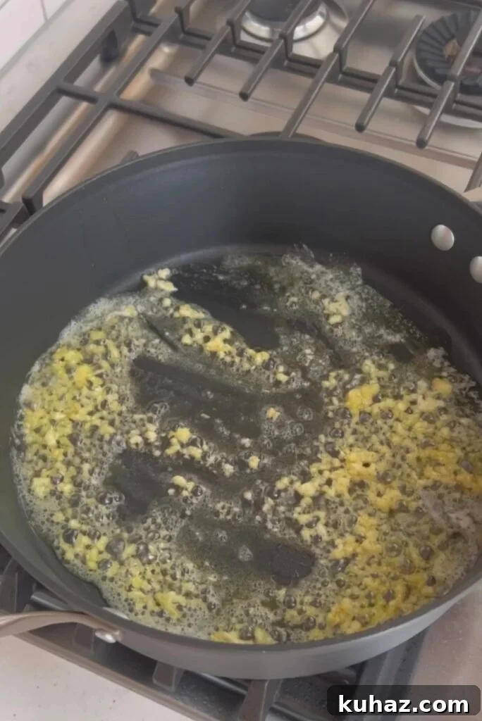 Garlic Sautéed Asparagus Recipe 4 An image of garlic, butter and oil cooking in a skillet.
