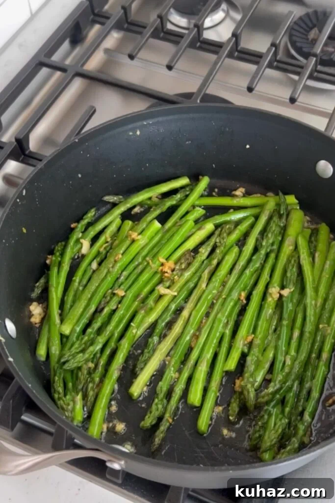 Garlic Sautéed Asparagus Recipe 5 An image of asparagus and garlic cooking in a skillet.