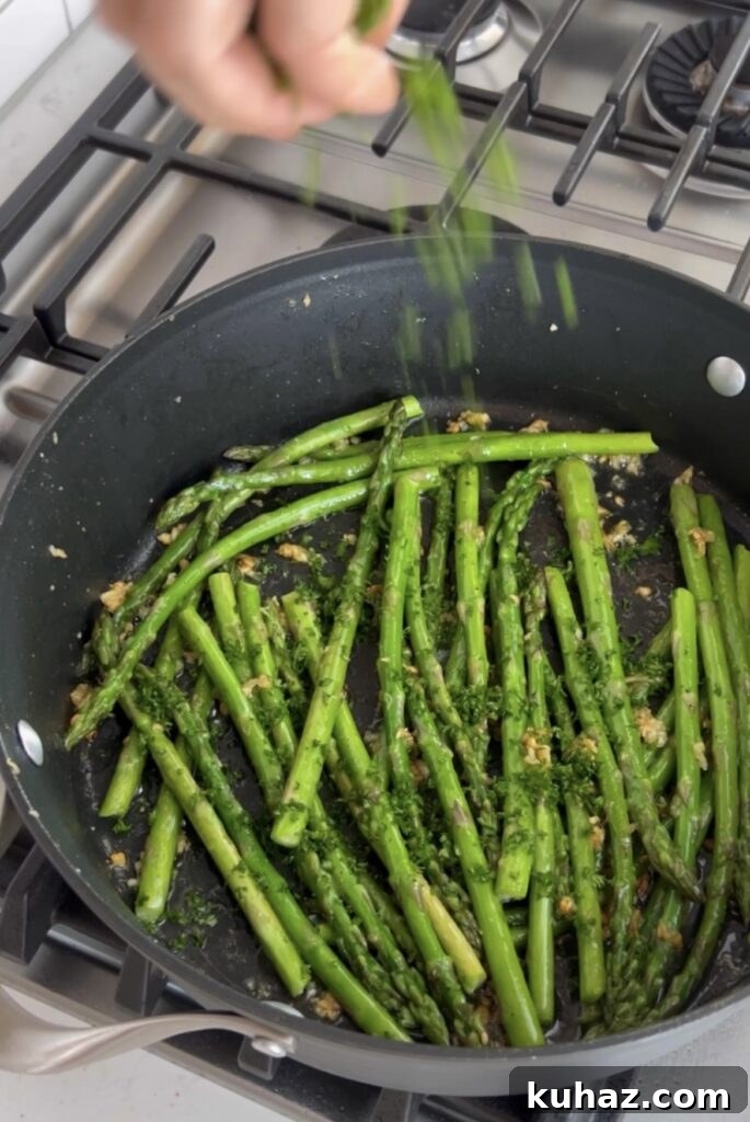 Garlic Sautéed Asparagus Recipe 6 Parsley being sprinkled into a skillet of sautéed asparagus.
