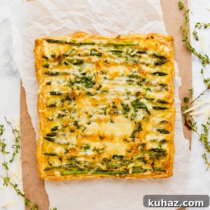 An overhead image of the asparagus puff pastry tart on a parchment lined cutting board with sprigs of thyme around it.