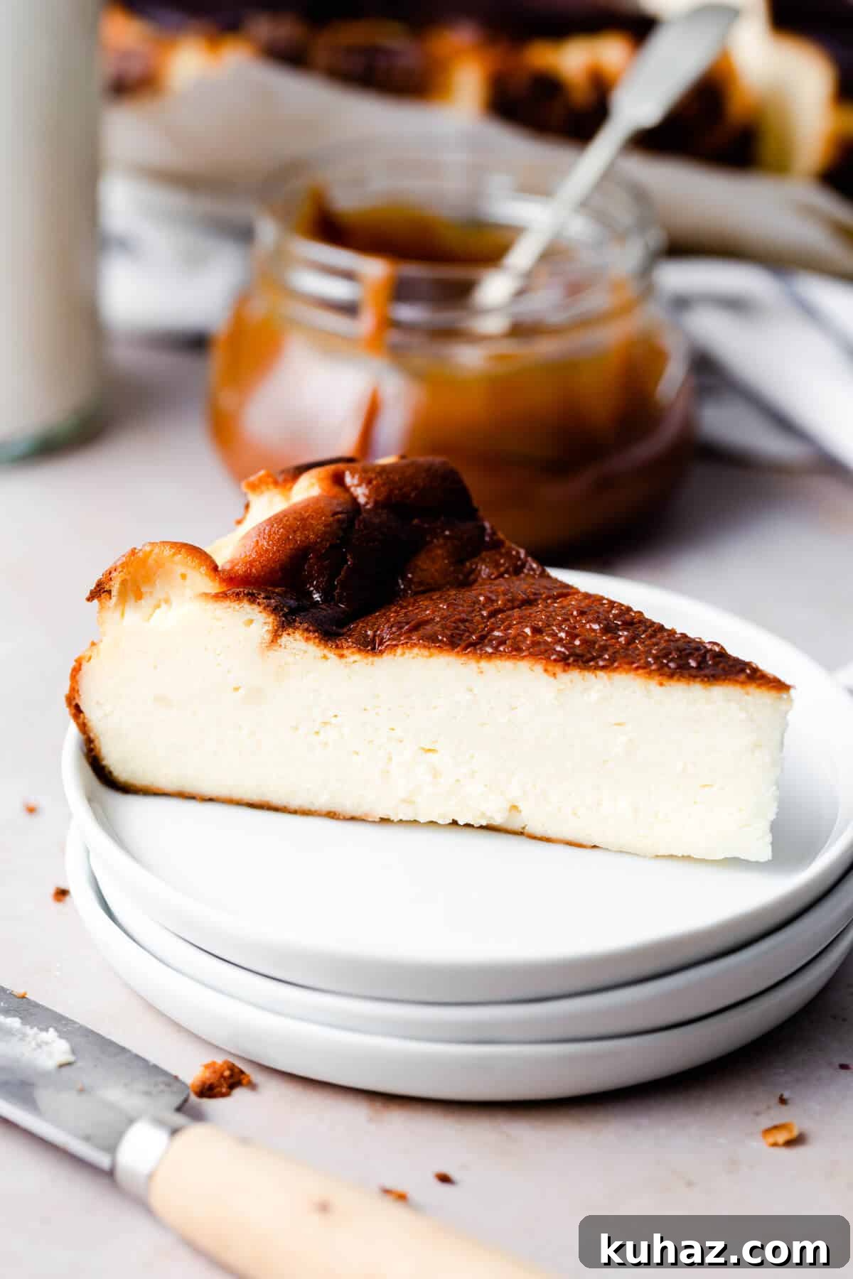 Basque Burnt Cheesecake Recipe — Silky, Caramelized Top 12 side close up of a slice of cheesecake on a stack of three white plates