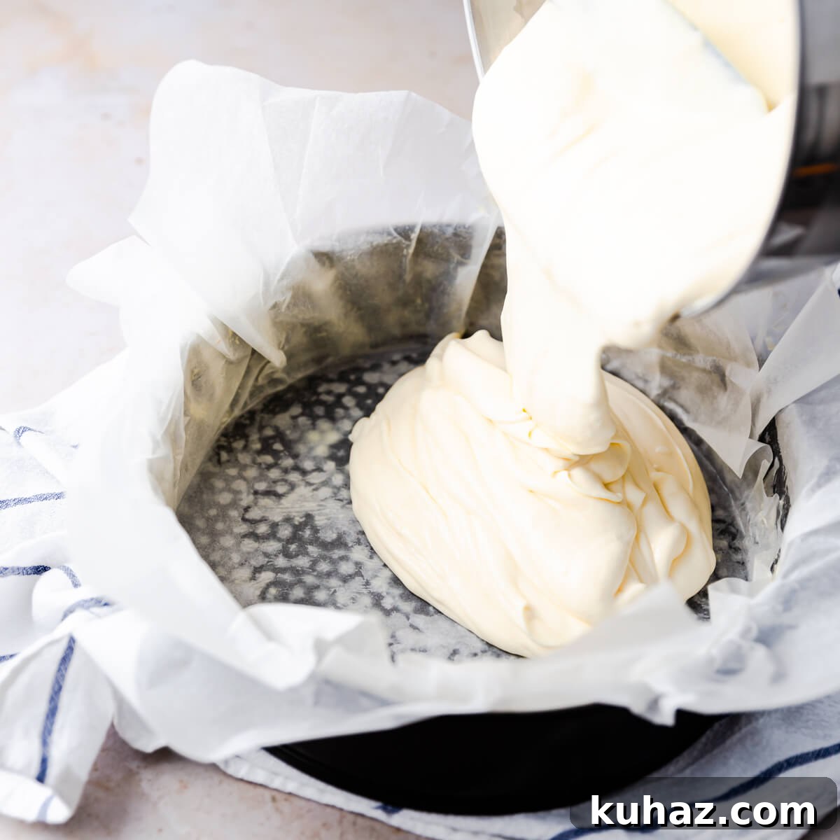 Basque Burnt Cheesecake Recipe — Silky, Caramelized Top 5 cheesecake batter being poured into baking tin lined with baking paper.