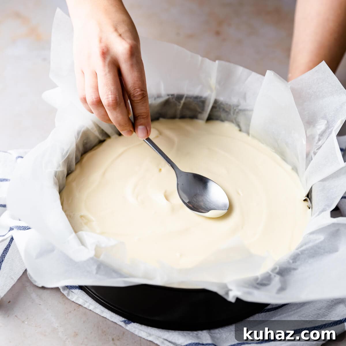 Basque Burnt Cheesecake Recipe — Silky, Caramelized Top 6 top of the cheesecake being smoothed out with the back of the spoon.