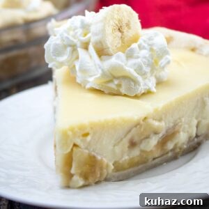 slice of pie on white plate. Topped with whipped cream and banana slice.