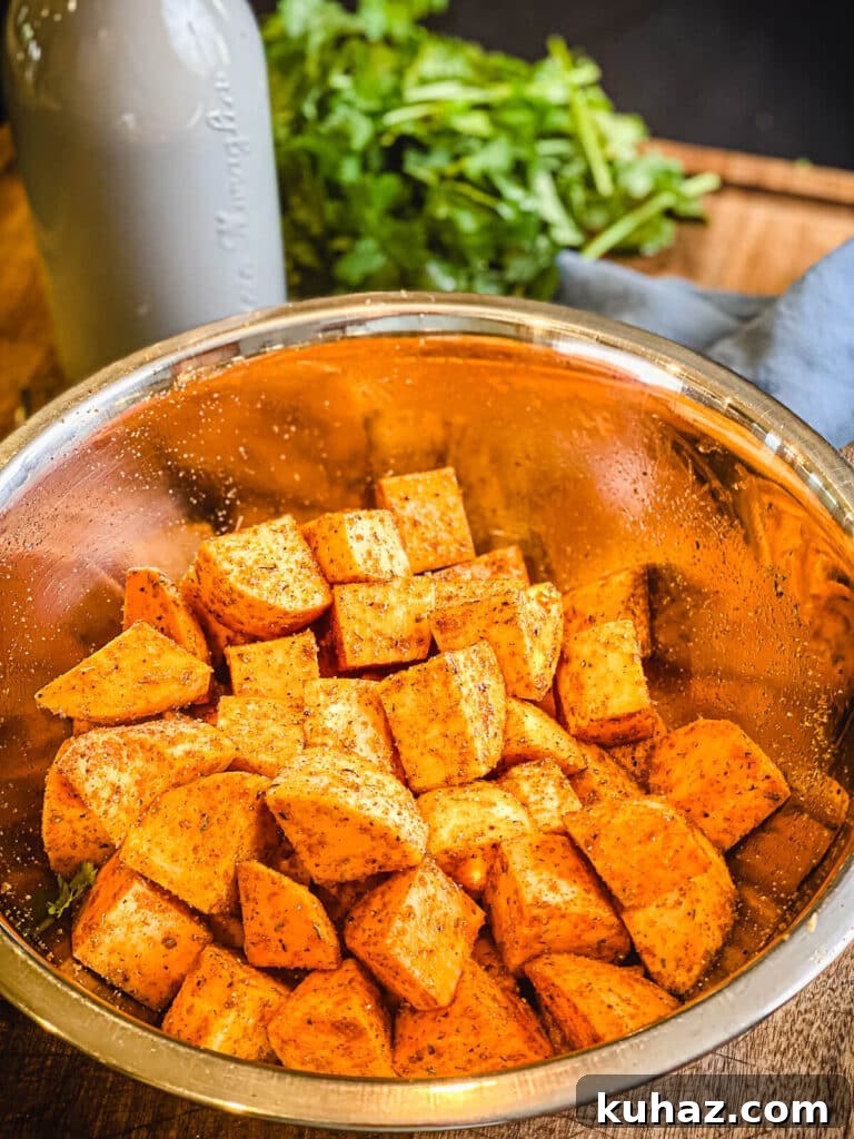 How to Grill or Roast Sweet Potatoes 8 raw sweet potato cubes in a bowl with seasoning