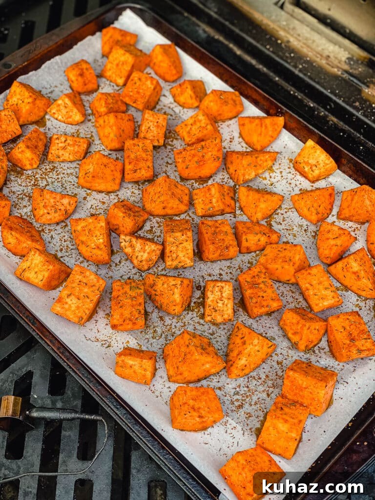 How to Grill or Roast Sweet Potatoes 10 sweet potatoes on a parchment lined baking sheet roasting on a grill.