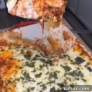 Cheesy baked lasagna being lifted from the pan