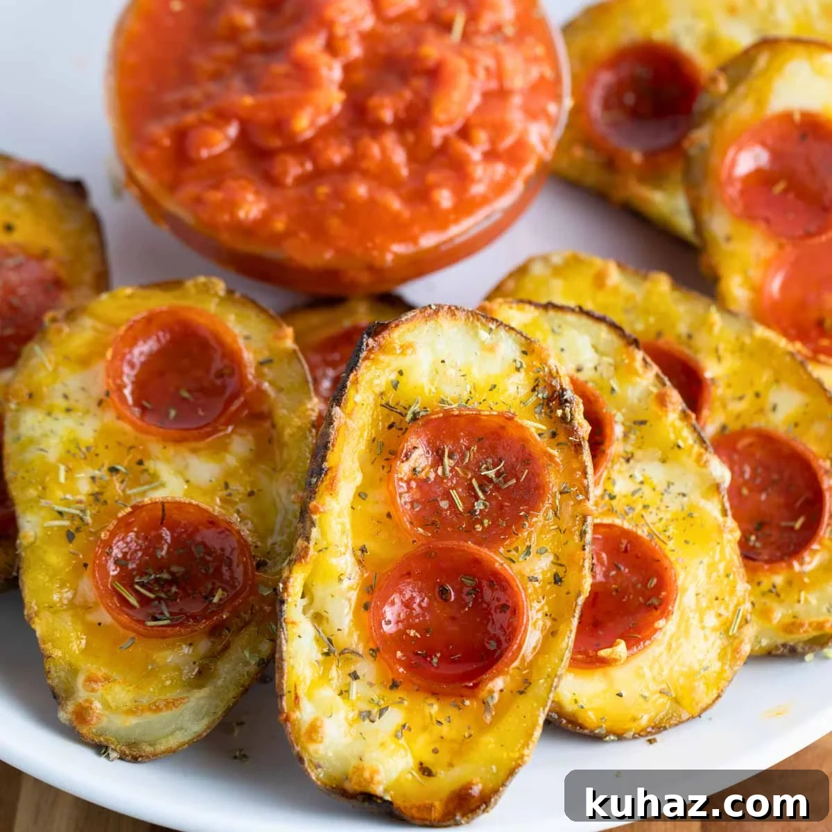 Pizza-Style Potato Skins Recipe with Pepperoni & Mozzarella 2 a plate of pizza potato skins with melted cheese, pepperoni, and Italian seasoning served with a side of marinara sauce.