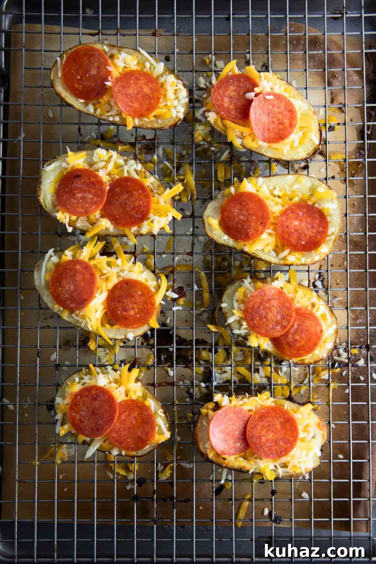 Pizza-Style Potato Skins Recipe with Pepperoni & Mozzarella 10 a closeup of potato skins arranged on a baking sheet with toppings added.