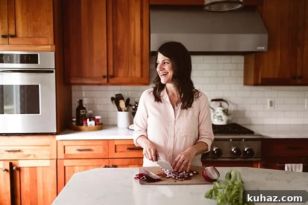 A woman cutting vegetables and smiling.