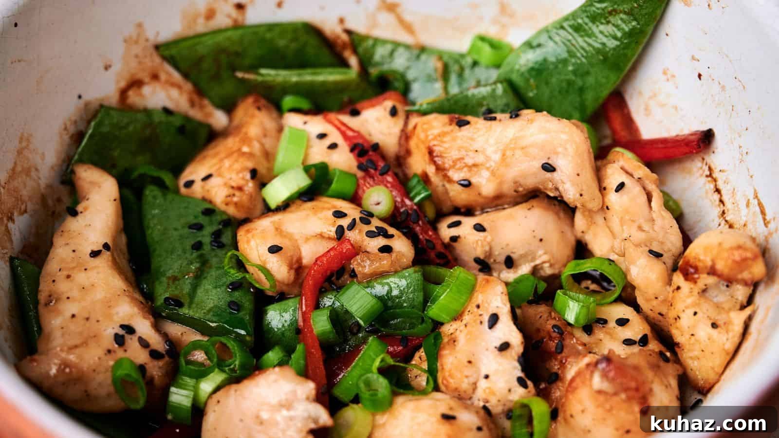 19 Asian Recipes That Fed My Family for $20 12 A close-up of a stir-fry dish featuring pieces of chicken, snap peas, red bell peppers, scallions, and black sesame seeds.