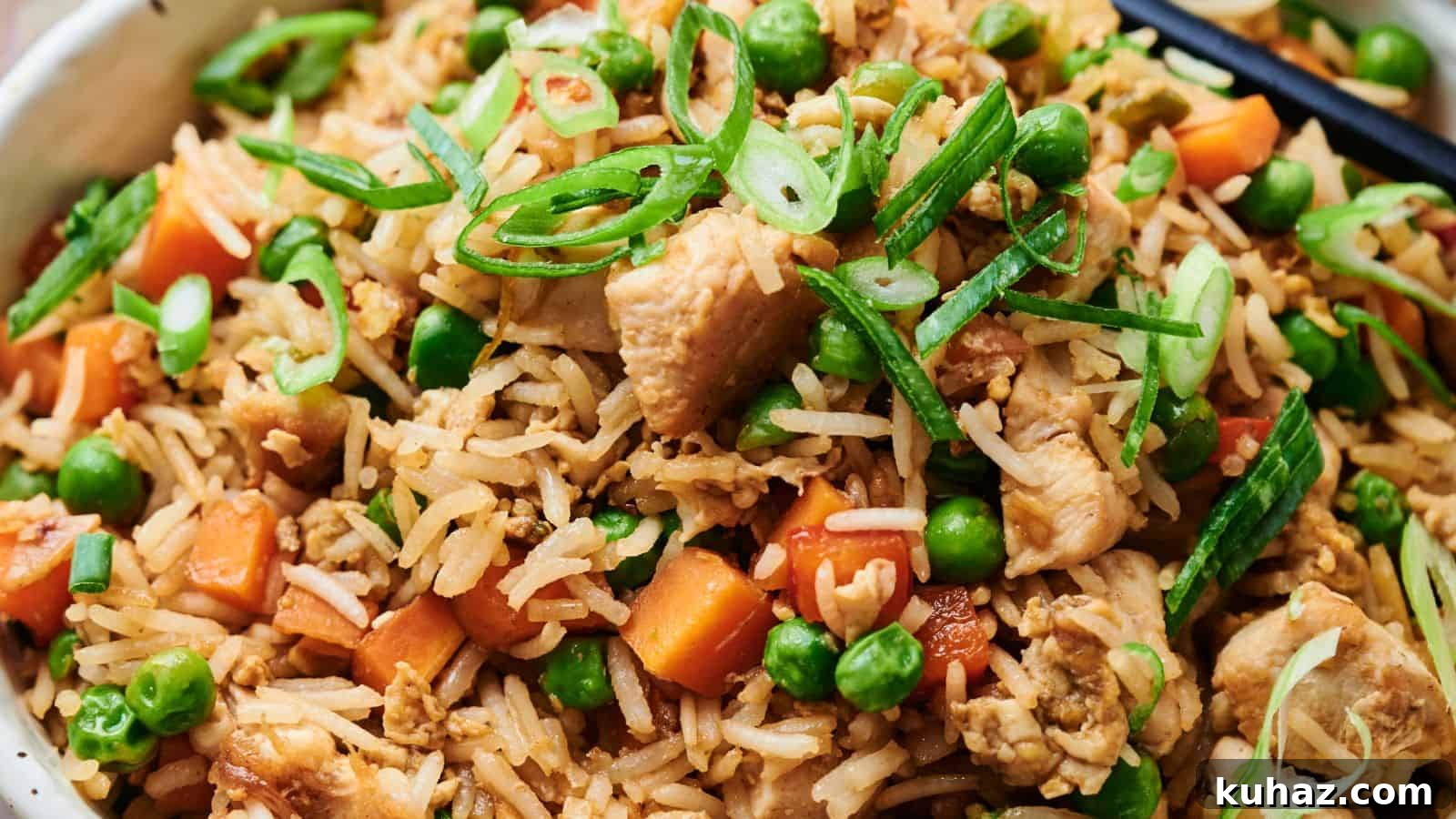 19 Asian Recipes That Fed My Family for $20 16 Close-up of chicken fried rice with peas, carrots, sliced green onions, and chopsticks.