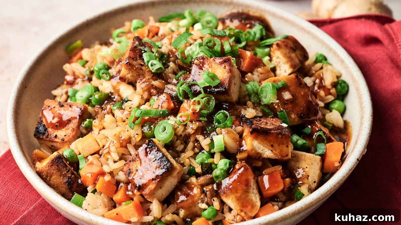 19 Asian Recipes That Fed My Family for $20 7 A bowl of fried rice with grilled tofu, diced carrots, peas, chopped green onions, and a drizzle of dark sauce, served on a red cloth.