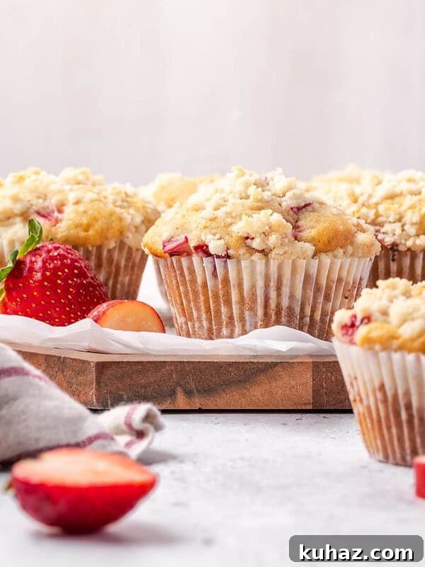 Strawberry rhubarb muffins with lemon streusel topping on a wooden board.