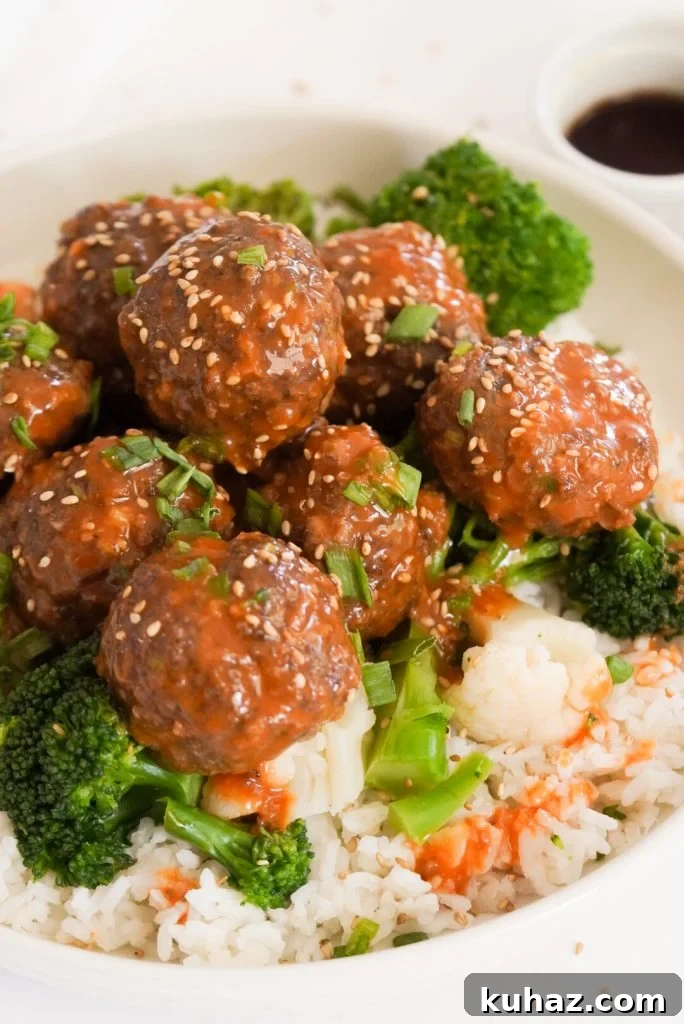 Spicy Firecracker Meatballs Recipe with Sweet Chili Glaze 12 45 degree angle shot of a bowl of meatballs over rice with homemade firecracker sauce.