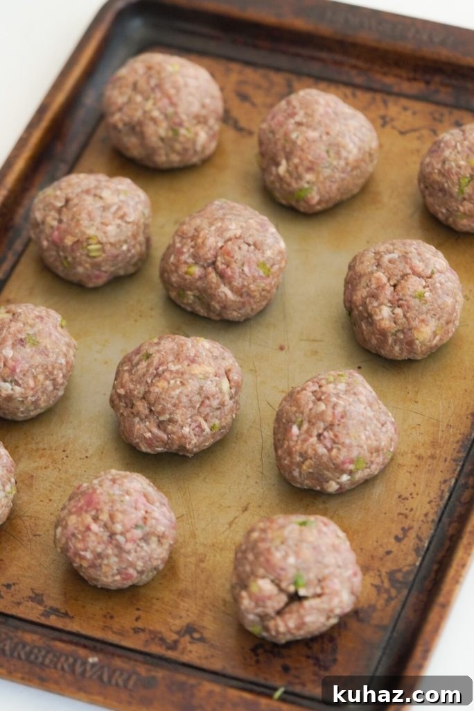 Spicy Firecracker Meatballs Recipe with Sweet Chili Glaze 8 12 raw meatballs rolled and placed on a baking sheet.