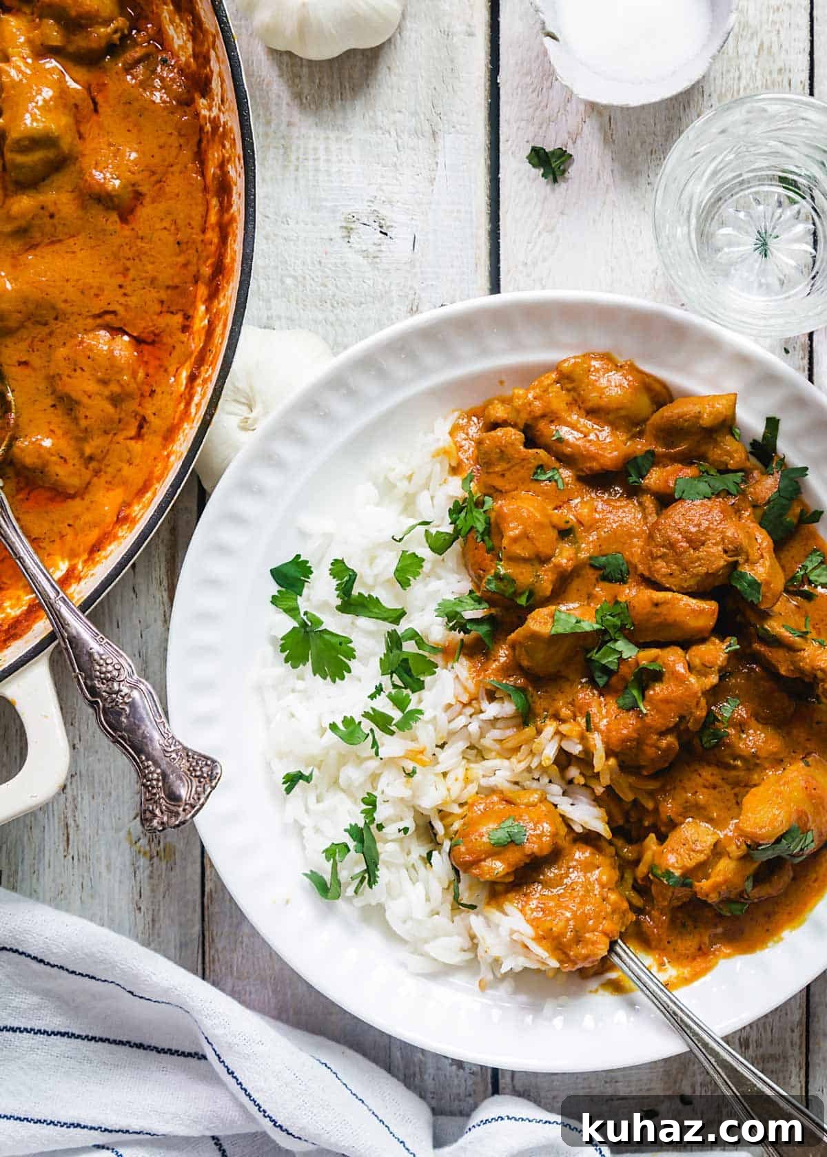 A bowl and a pan with chicken tikka, rice, and spoons.