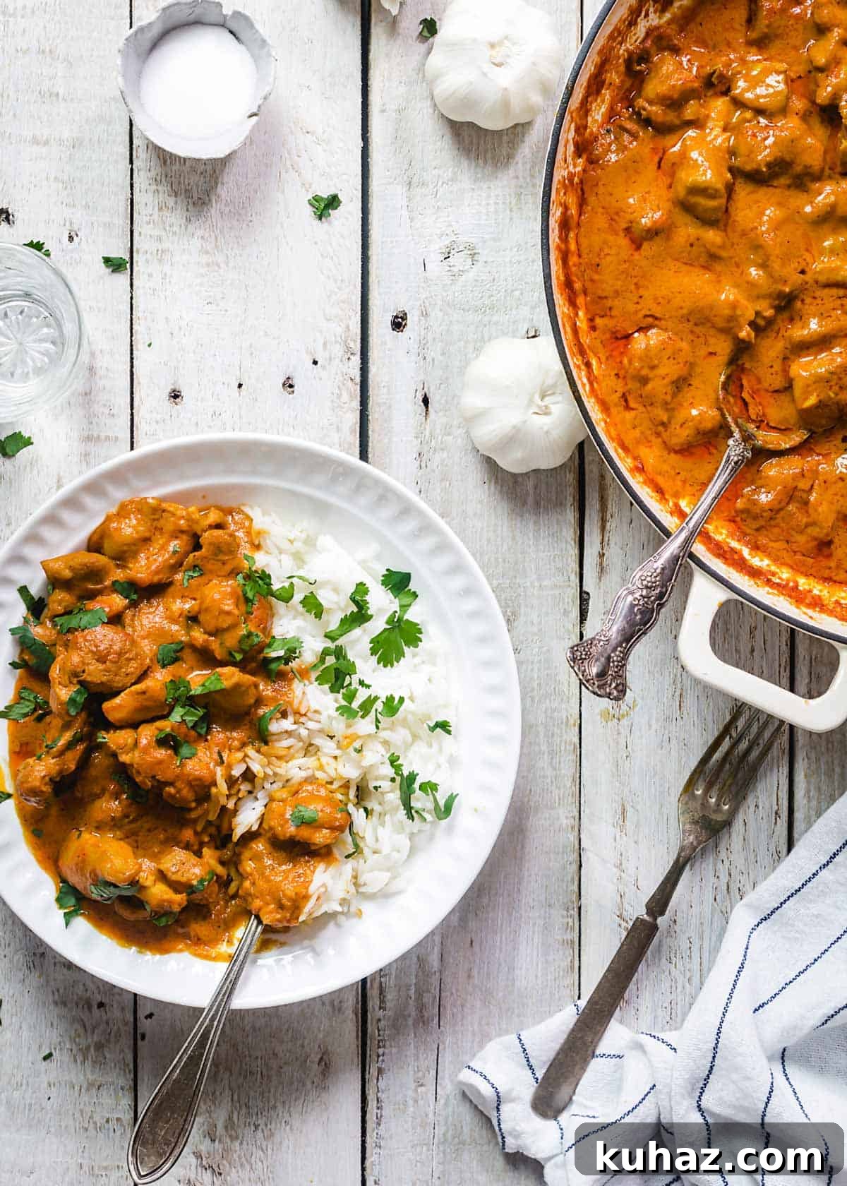 A bowl and a pan with chicken tikka on a table.