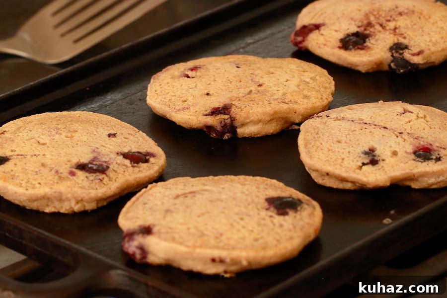 Fluffy Gluten Free Vegan Blueberry Oatmeal Pancakes 6 Blueberry oatmeal pancakes cooking on a cast iron griddle
