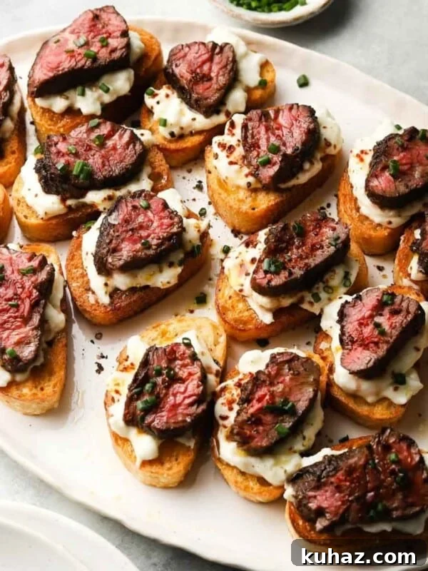 14 Crowd-Pleasing Game Day Appetizers 17 Crostini topped with creamy burrata, seared steak, and fresh herbs on a white platter.