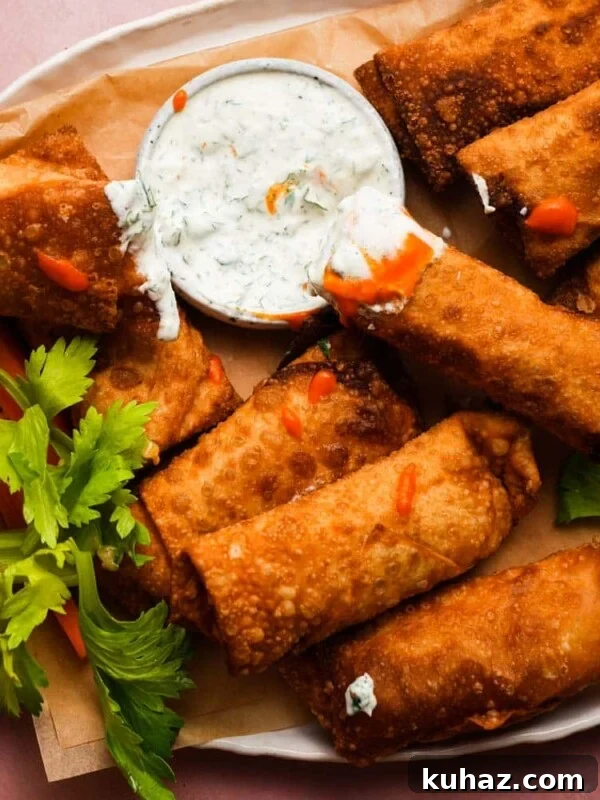 14 Crowd-Pleasing Game Day Appetizers 18 Crispy buffalo chicken egg rolls with dipping sauce and celery garnish on a platter.