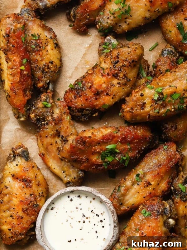 14 Crowd-Pleasing Game Day Appetizers 19 Crispy lemon pepper wings on parchment with dipping sauce garnished with herbs.