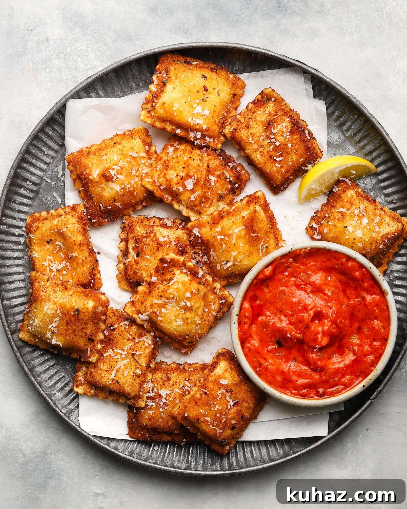 14 Crowd-Pleasing Game Day Appetizers 4 Golden toasted ravioli with tomato sauce and lemon wedge on a plate.